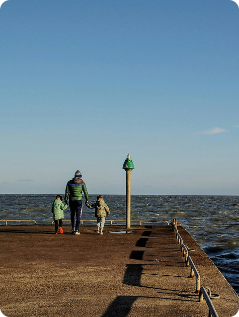 Parent walking with children near the harbour representing family support and daily life in Ireland